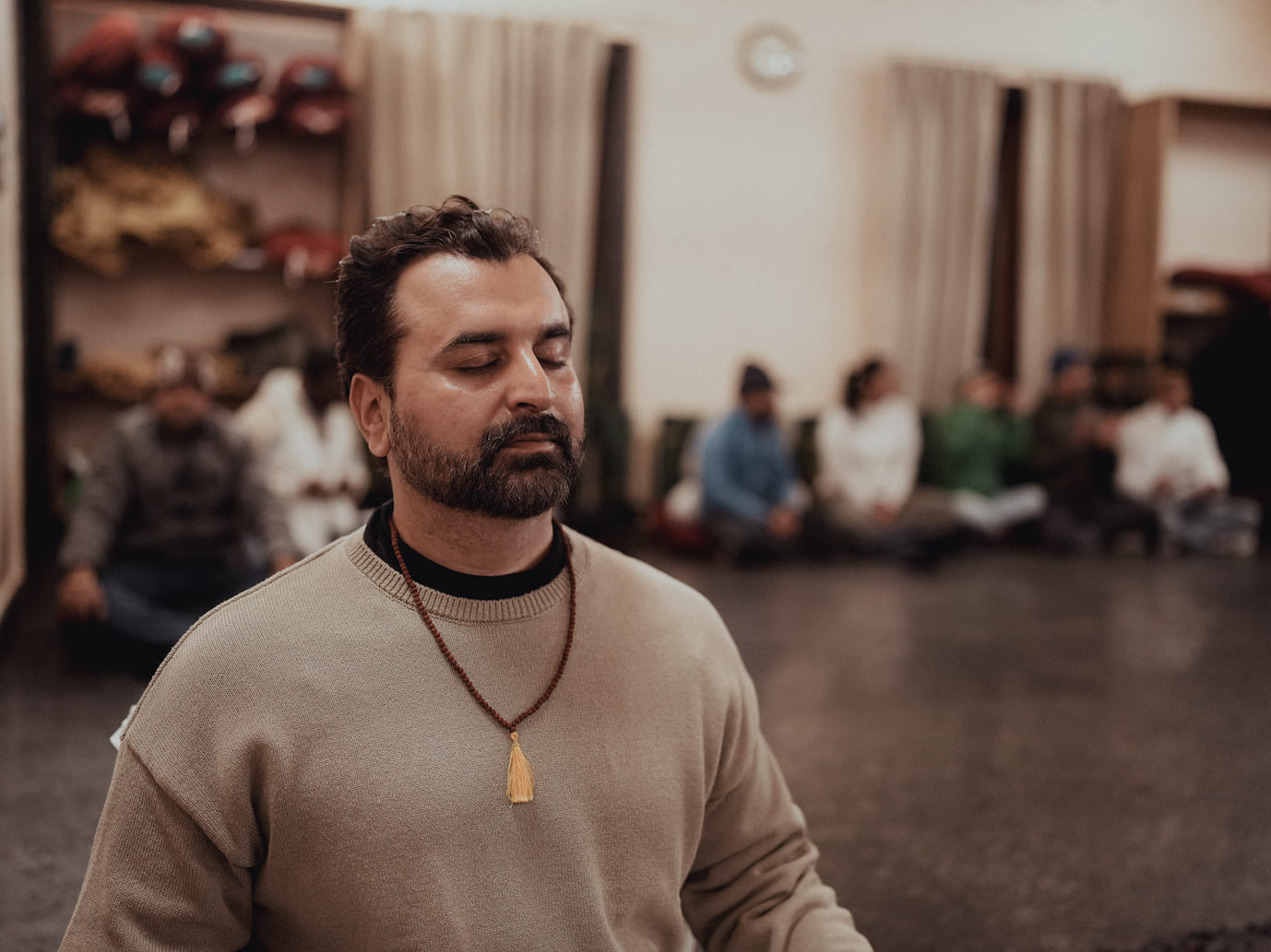 Guest meditating with mala beads in community meditation hall