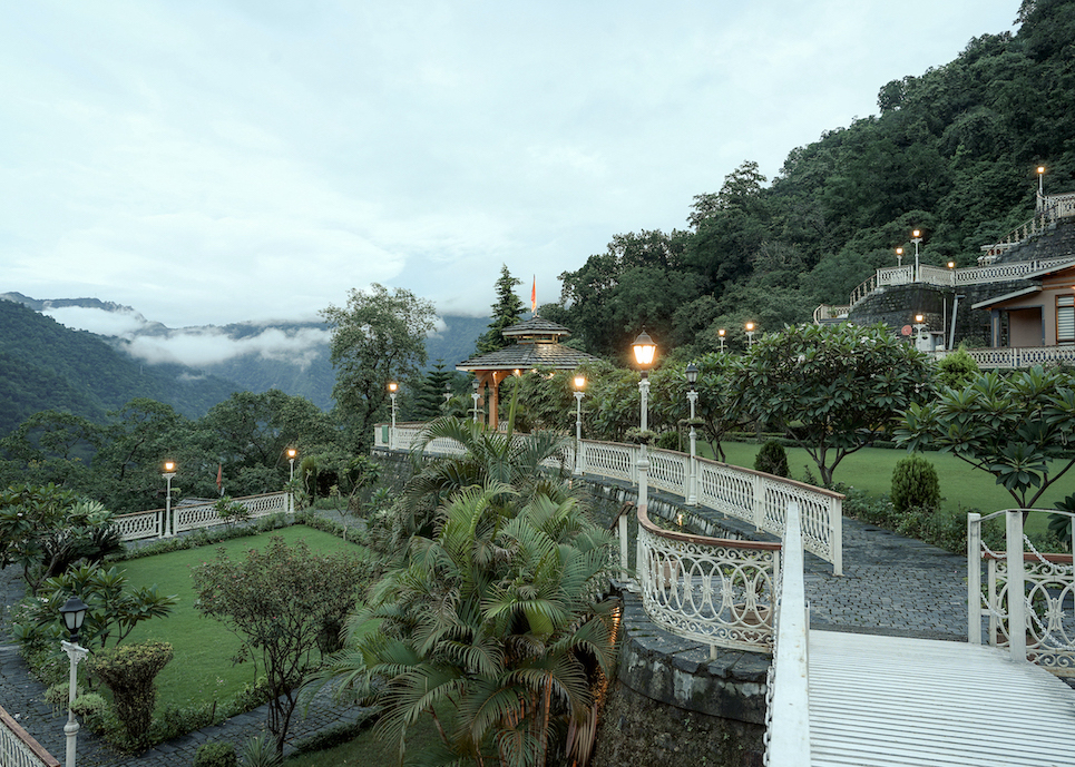 The peaceful manicured grounds of Rishikesh Yogpeeth ashram with valley view at dusk