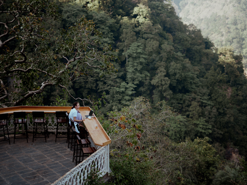 A student studies independently at the cliff-edge café overlooking the Himalayan forest valley