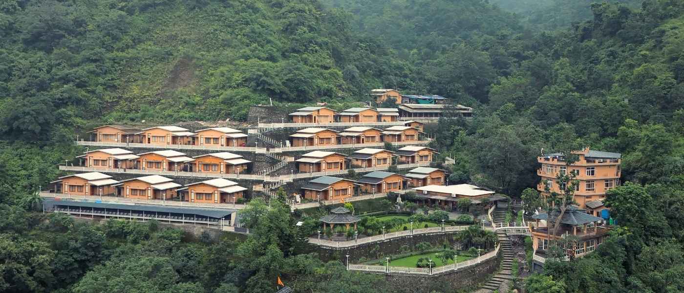 Aerial view of Rishikesh Yogpeeth ashram cottages amid Himalayan forest, residential yoga teacher training in Rishikesh India 